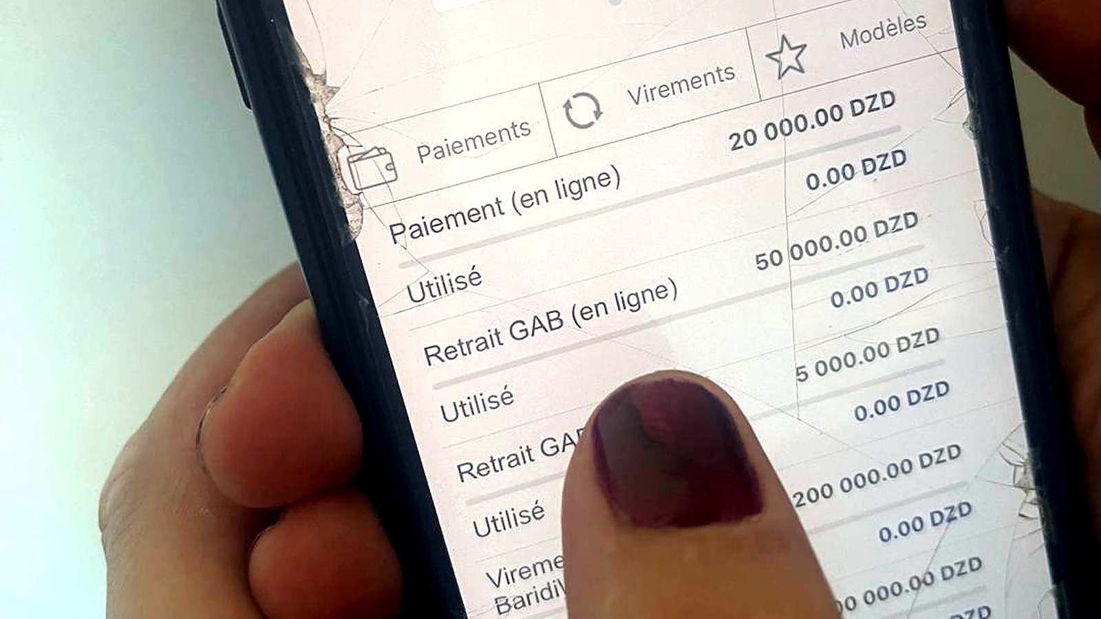 Utilisateur consultant l’application BaridiMob sur un téléphone à écran fissuré en Algérie.