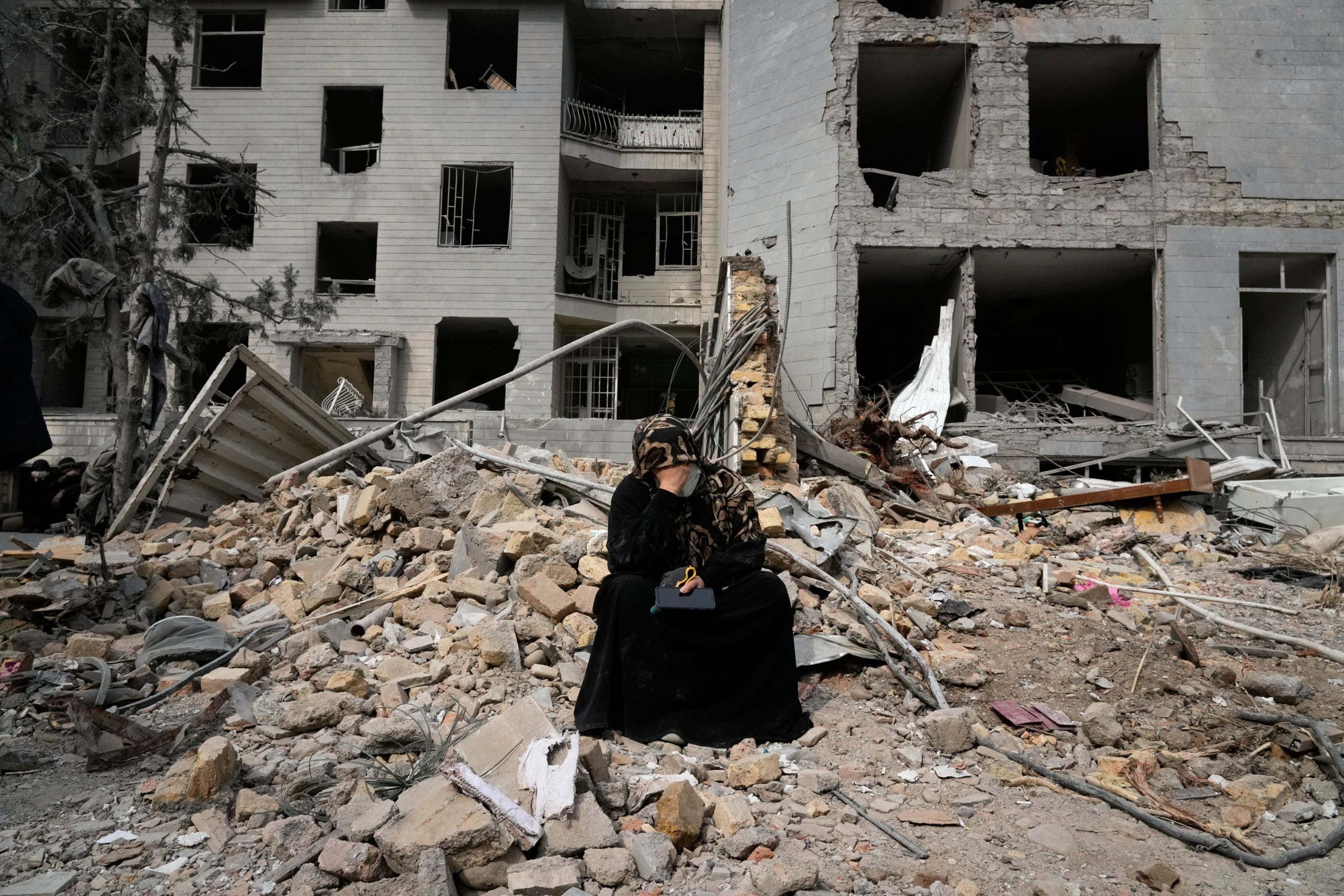 Une Iranienne assise parmi les gravats devant un bâtiment résidentiel endommagé à Téhéran.